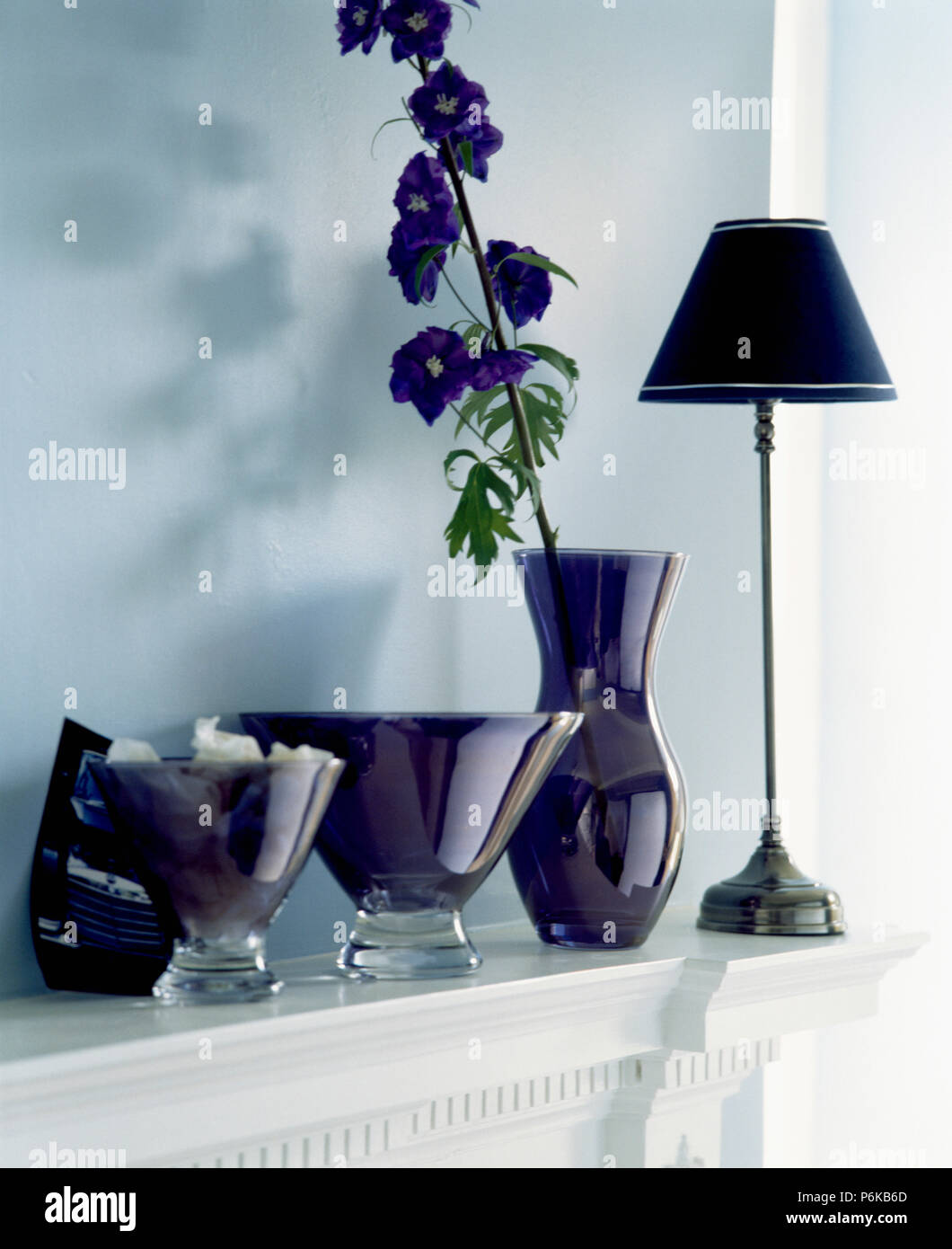 Close-up de pourpre foncé provenait des vases et grand vase avec delphinium bleu unique sur la cheminée avec lampe noire Banque D'Images