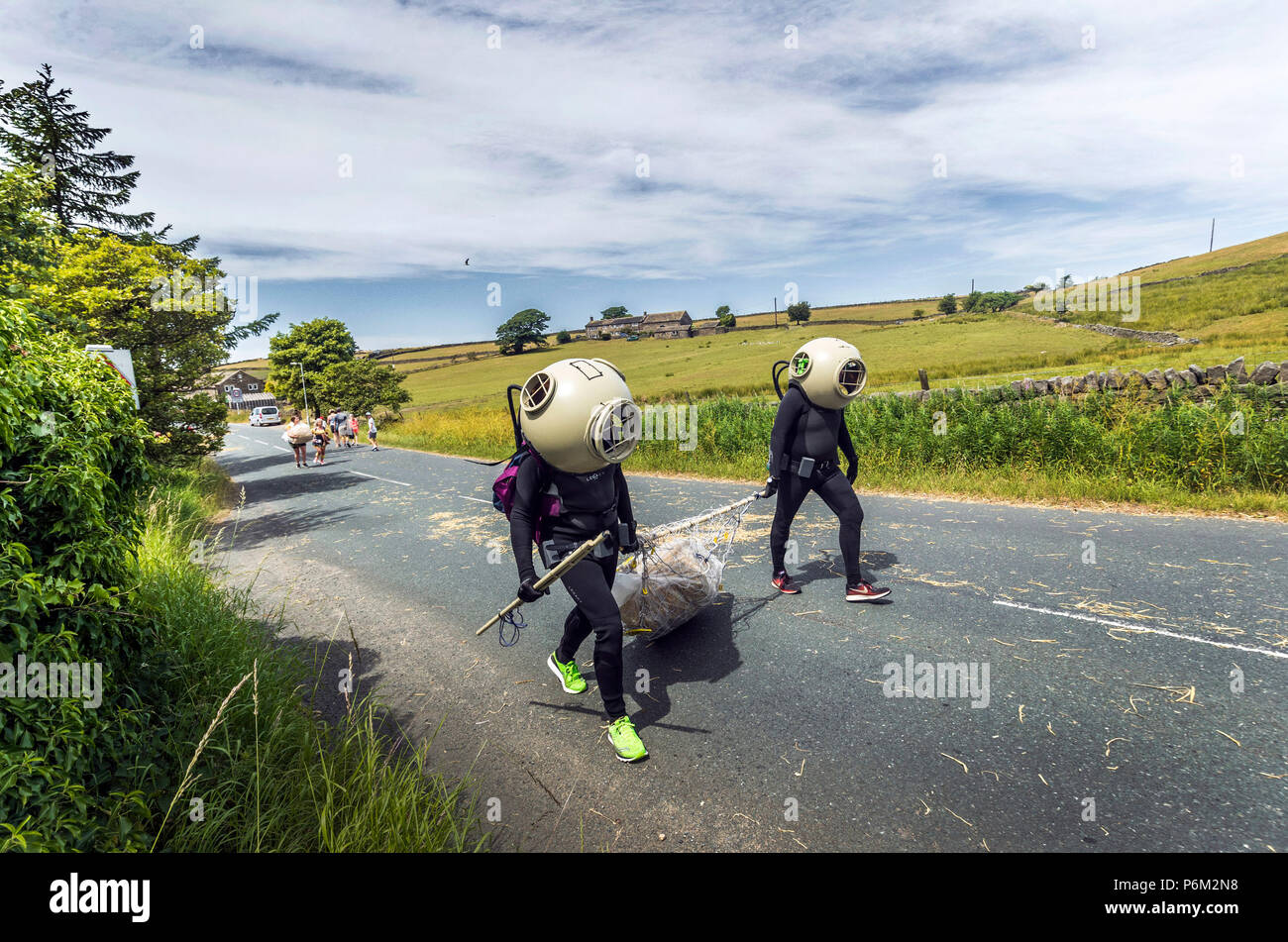 Concurrents prend part à la ferme de la course de la paille dans le Yorkshire, un 2,5 km course en robe portant une botte de paille de 20 kg, tout en arrêtant de pintes de bière le long de la route. Banque D'Images