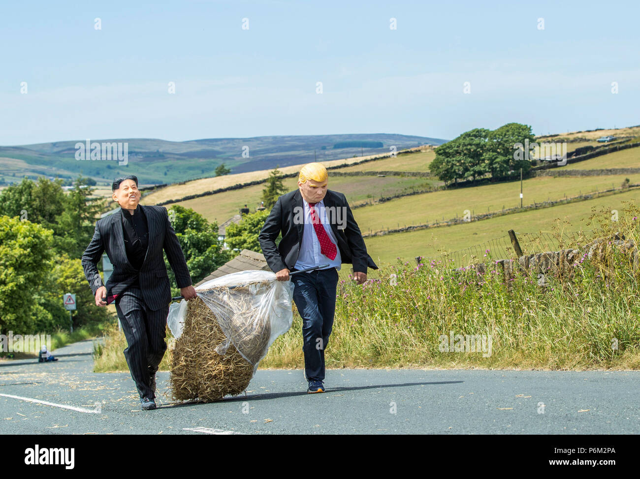 Concurrents prend part à la ferme de la course de la paille dans le Yorkshire, un 2,5 km course en robe portant une botte de paille de 20 kg, tout en arrêtant de pintes de bière le long de la route. Banque D'Images