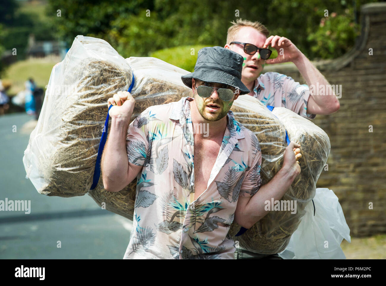 Concurrents prend part à la ferme de la course de la paille dans le Yorkshire, un 2,5 km course en robe portant une botte de paille de 20 kg, tout en arrêtant de pintes de bière le long de la route. Banque D'Images