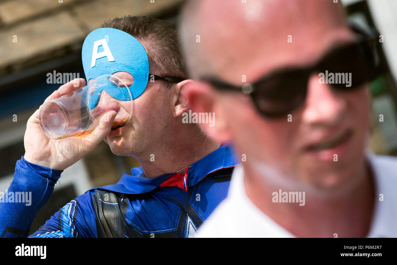 Concurrents prend part à la ferme de la course de la paille dans le Yorkshire, un 2,5 km course en robe portant une botte de paille de 20 kg, tout en arrêtant de pintes de bière le long de la route. Banque D'Images