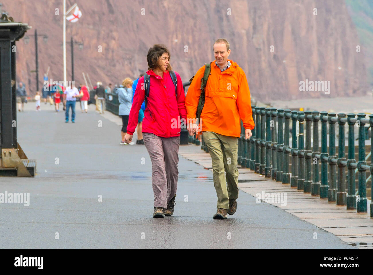 La ville de Sidmouth, Devon, UK. 1er juillet 2018. Météo britannique. Les visiteurs de la station balnéaire de Sidmouth dans le Devon marcher le long de la mer comme la ville attrape le bord d'une adoption forte pluie douche. Crédit photo : Graham Hunt/Alamy Live News Banque D'Images