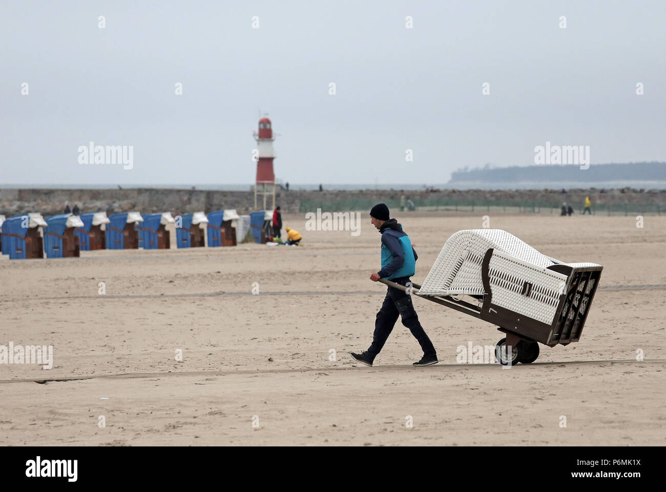 Warnemuende, homme apporte une chaise de plage à la plage Banque D'Images