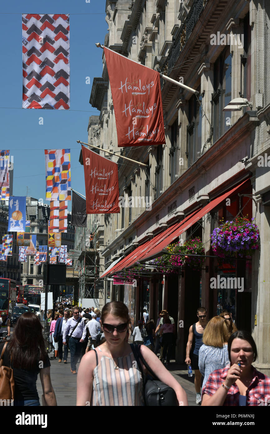 Les consommateurs, les touristes et les employés de bureau passent devant le navire amiral Hamleys toy store sur Regent Street dans le centre de Londres, dans le soleil d'été. Banque D'Images