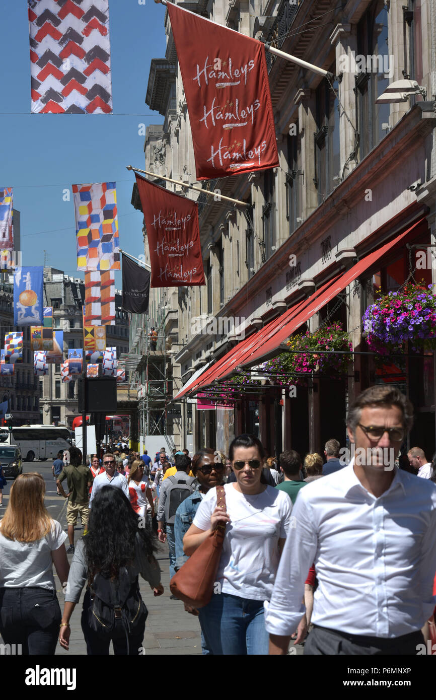 Les consommateurs, les touristes et les employés de bureau passent devant le navire amiral Hamleys toy store sur Regent Street dans le centre de Londres, dans le soleil d'été. Banque D'Images