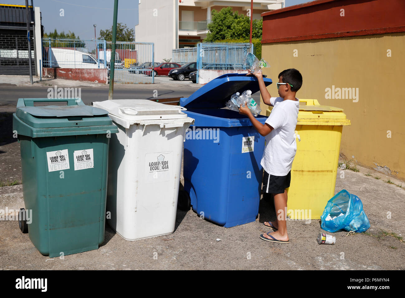 Garçon de 11 ans à jeter les ordures dans les bacs de recyclage dans le Salento, en Italie. Banque D'Images