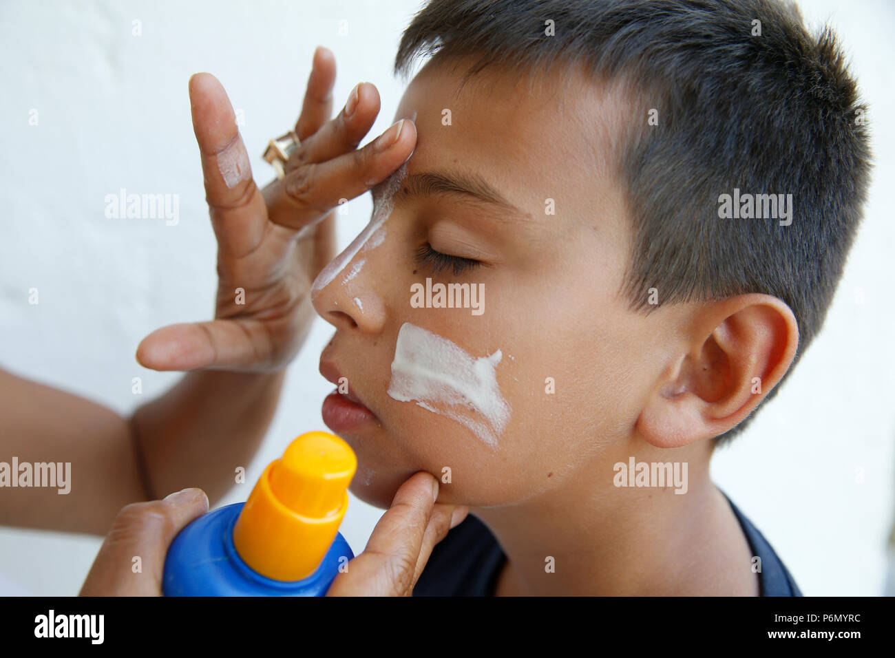 Mother putting crème solaire sur le visage de son fils dans le Salento, en Italie. Banque D'Images