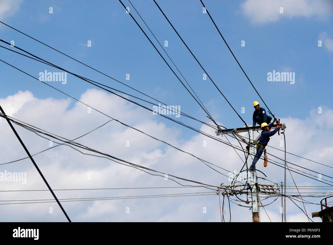 Electrician repairing Maintenance électricité pylône. Cai Be. Le Vietnam. Banque D'Images