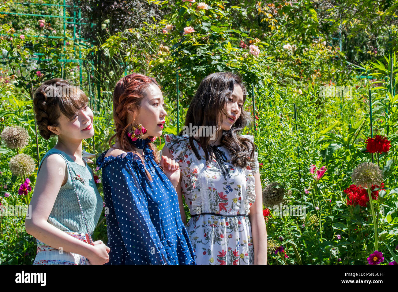 Les jeunes femmes qui posent les touristes chinois parmi les fleurs dans le jardin de la maison de peintre impressionniste Claude Monet à Giverny, Eure, Normandie, France Banque D'Images