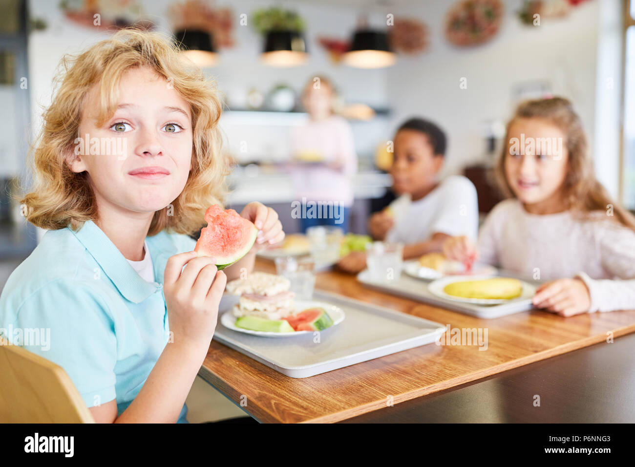 Happy boy et ses amis mangent à la cantine de l'école élémentaire Banque D'Images
