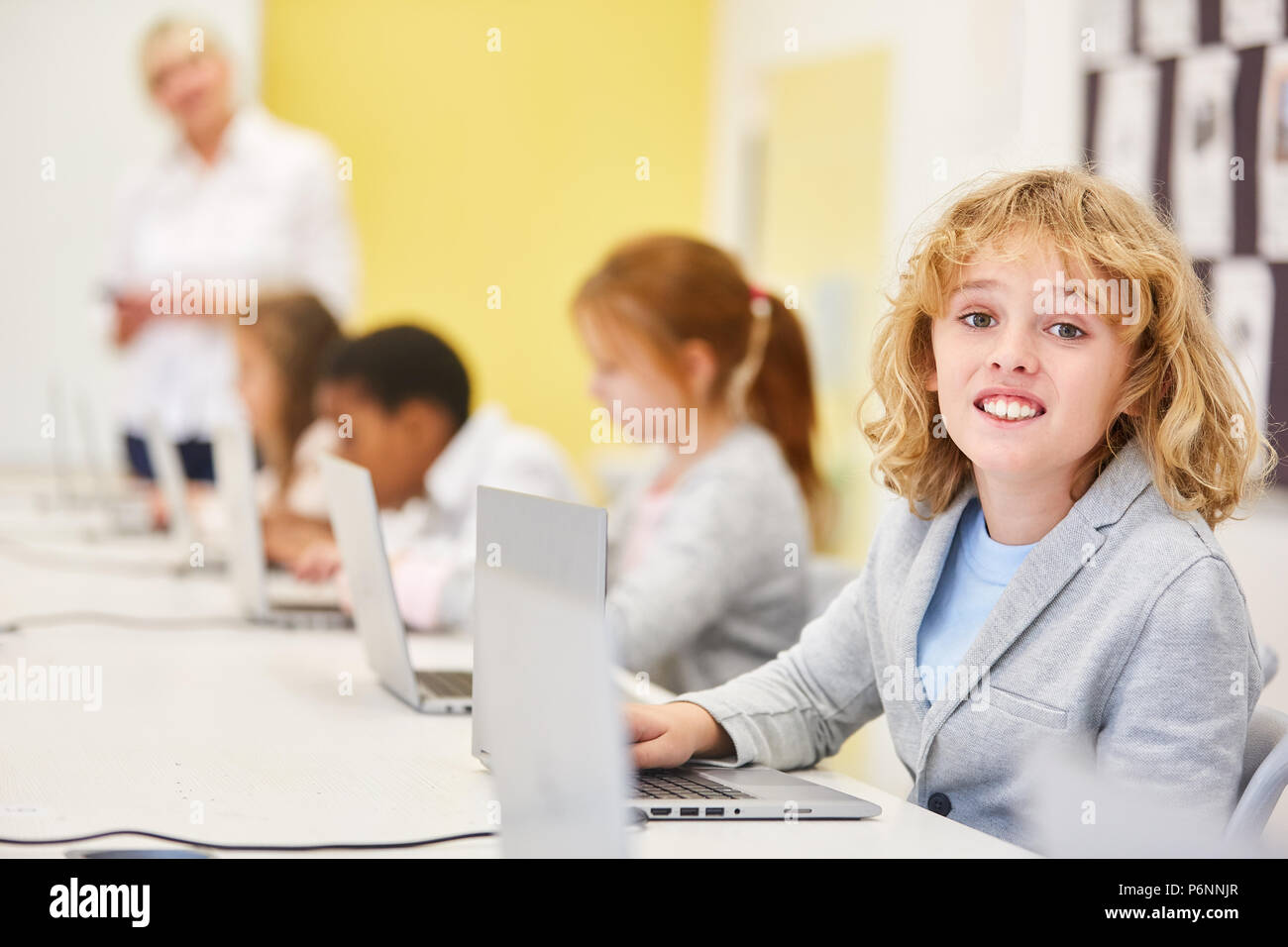 Garçon blond comme un étudiant en informatique à l'école primaire à l'enseignement d'une l'ordinateur portable Banque D'Images