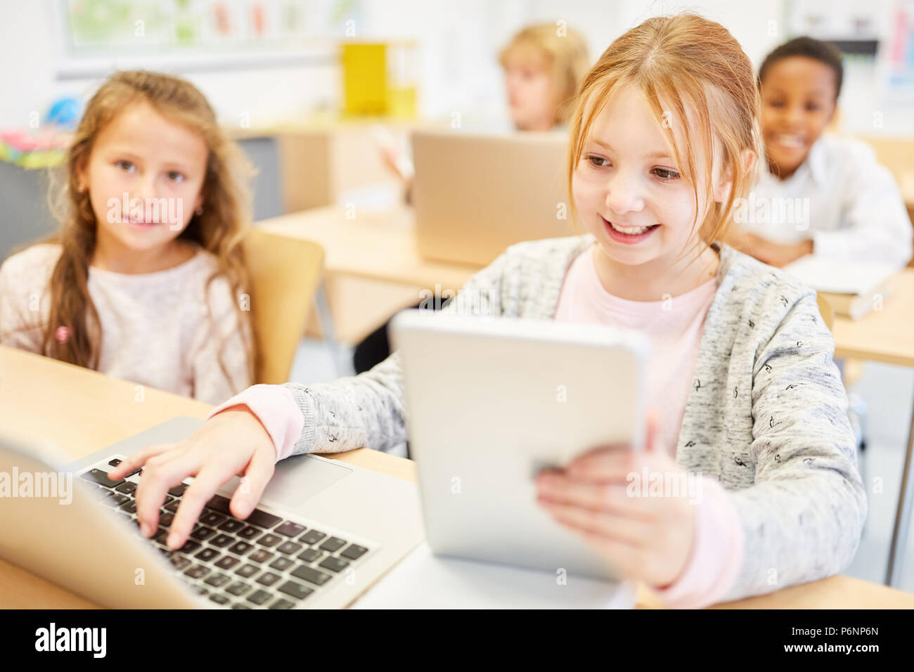 Les enfants en informatique apprendre des leçons avec ordinateur portable et tablette de l'école élémentaire Banque D'Images