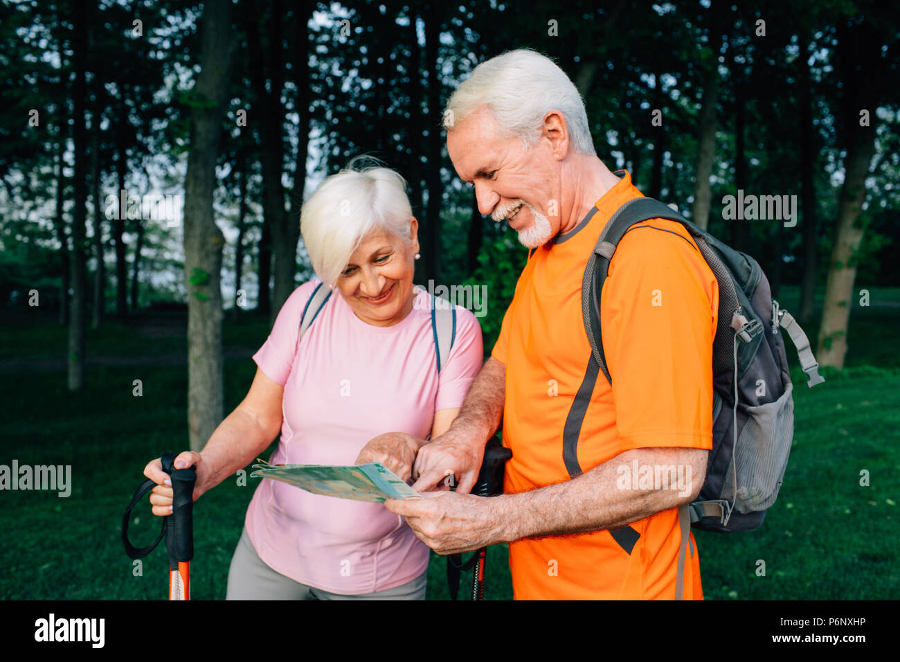 Couple de personnes âgées les randonneurs contrôle map in woods Banque D'Images
