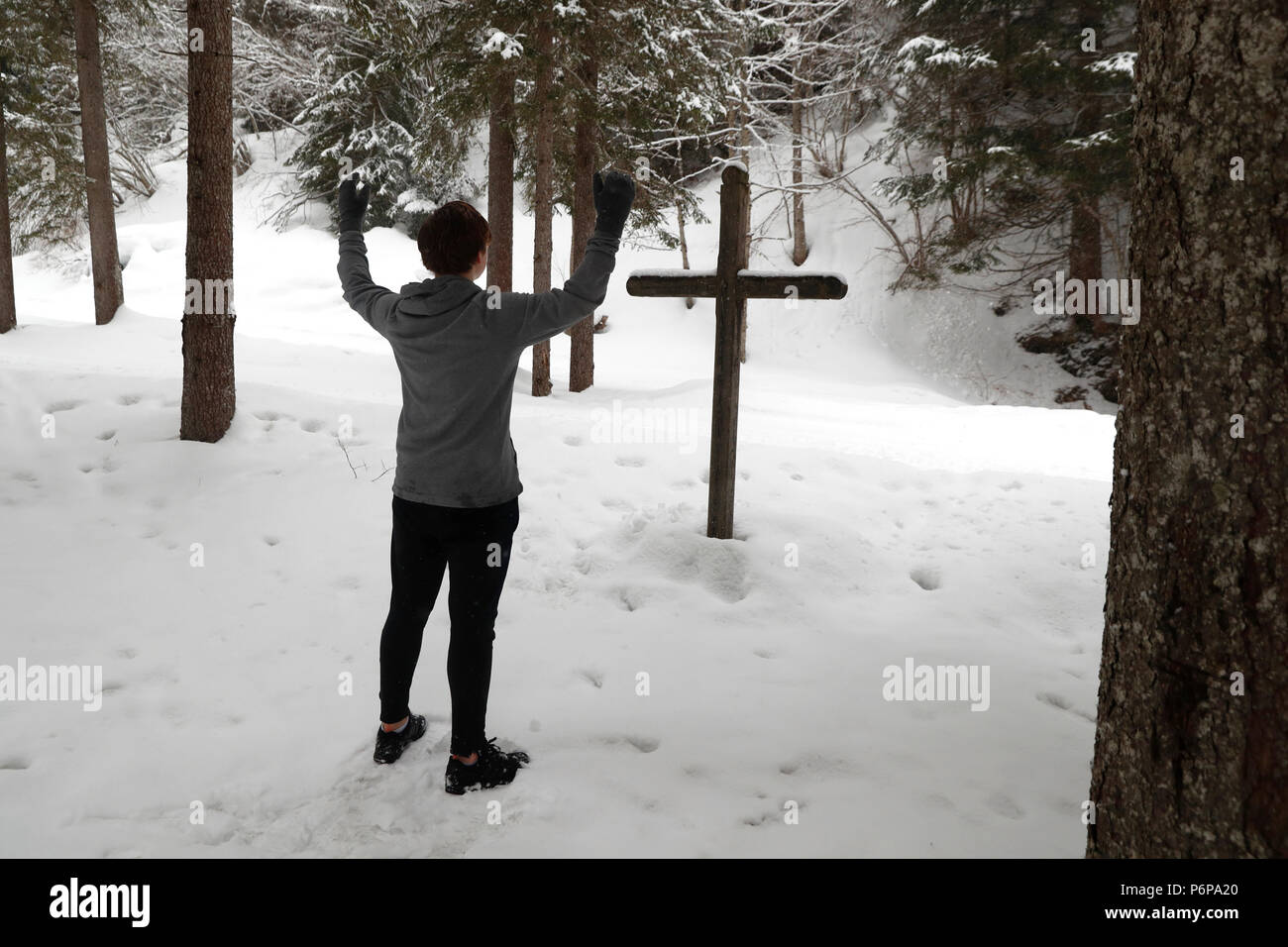 Christian garçon priant en hiver en face d'une croix en bois. Les Contamines. La France. Banque D'Images