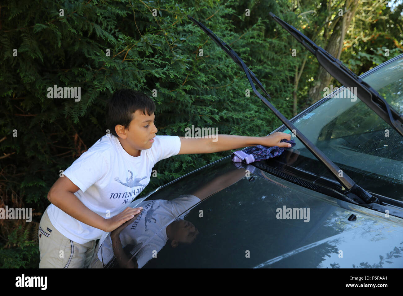 Garçon de 11 ans lave une voiture. La France. Banque D'Images