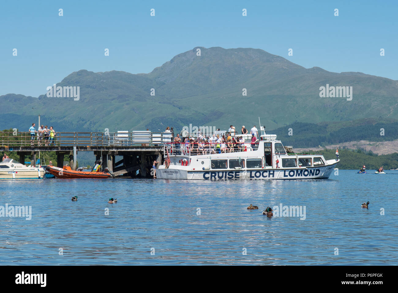 Le Loch Lomond - Luss jetée sur une chaude journée d'été avec Ben Lomond derrière, avec bateau de croisière et ramasser des passagers, Ecosse, Royaume-Uni Banque D'Images