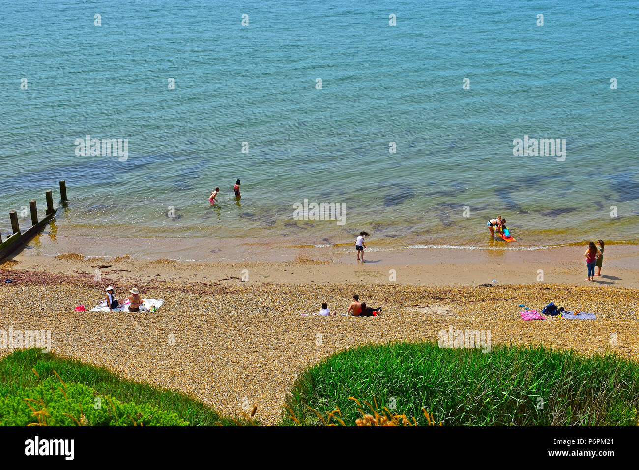 Enfants bravant la mer glaciale sous le soleil d'été à Milford on Sea, Hampshire Banque D'Images