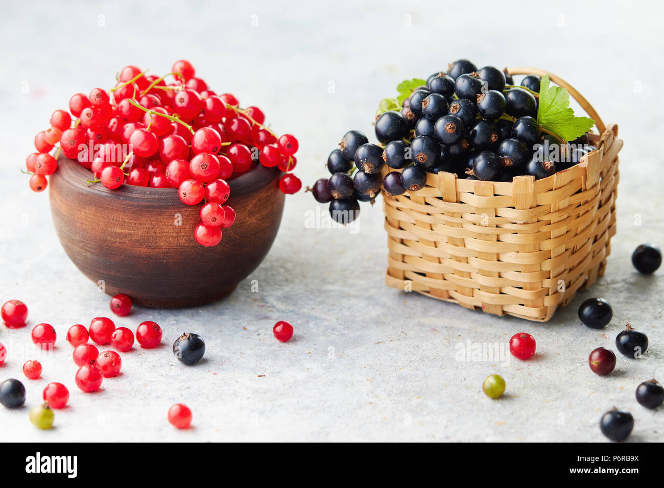 Petits fruits fraîchement cueillis. Dans un bol de groseilles et à proximité d'un petit panier en osier de cassis frais. Banque D'Images