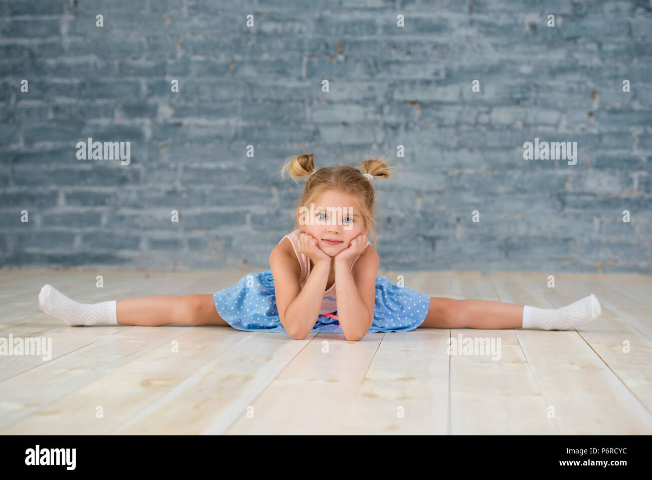 Petite fille est assise sur une chaîne. Les jeunes filles faisant de la gymnastique. Banque D'Images