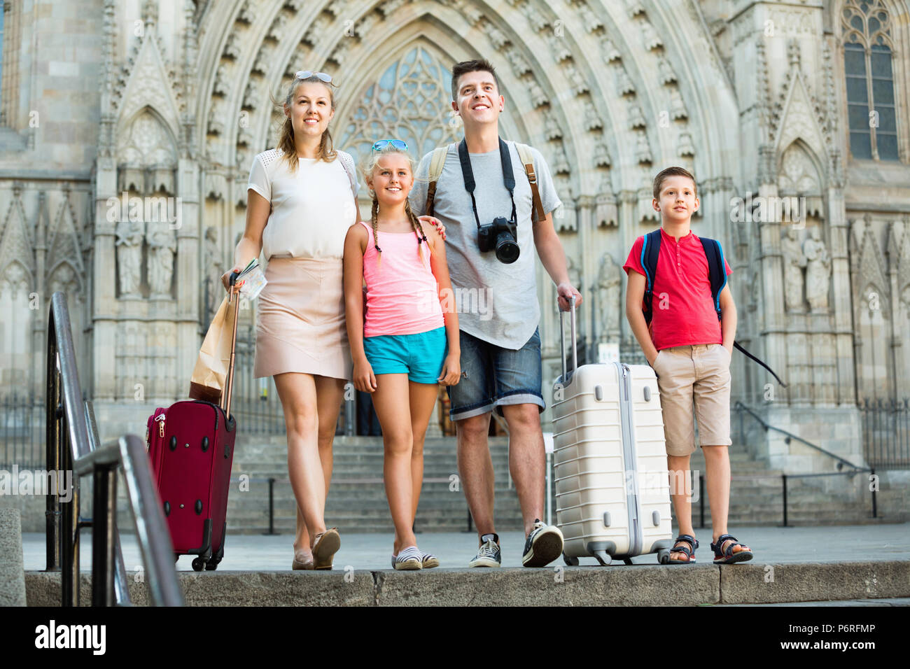 Friendly positive de la famille voyageant avec des bagages en flânant le long de quatre European city street Banque D'Images