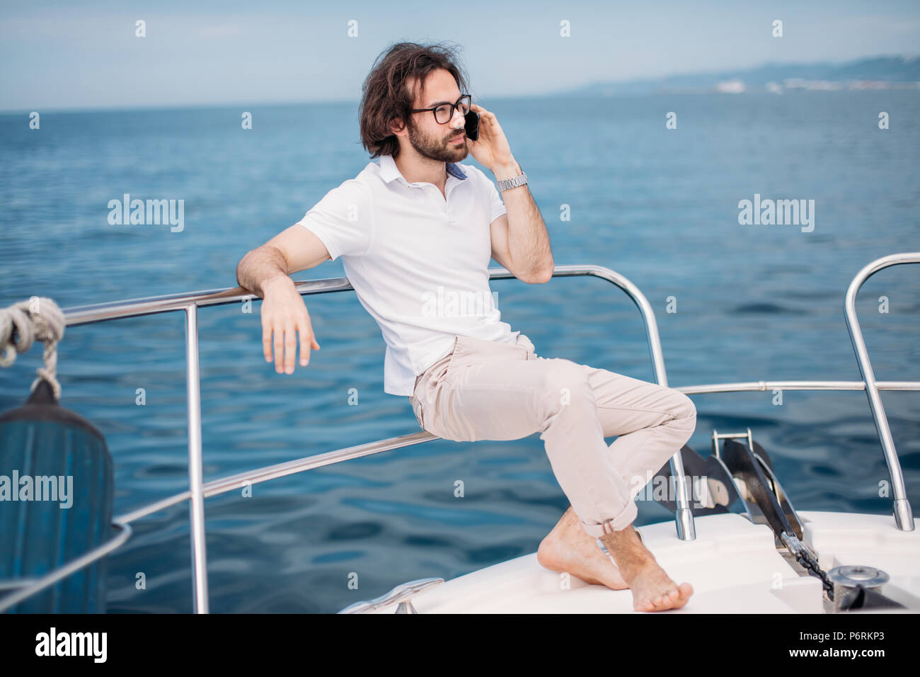 Jeune homme barbu sur un yacht de luxe avec une vue magnifique sur la mer. La voile. Yachts de luxe. Vacances d'été et voyage concept. Banque D'Images