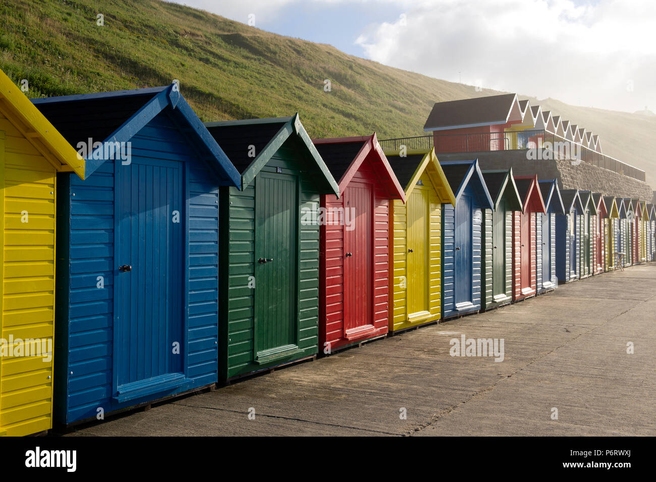 Les cabines de plage multicolores surplombant la plage de Whitby sur la côte du Yorkshire du Nord. Banque D'Images