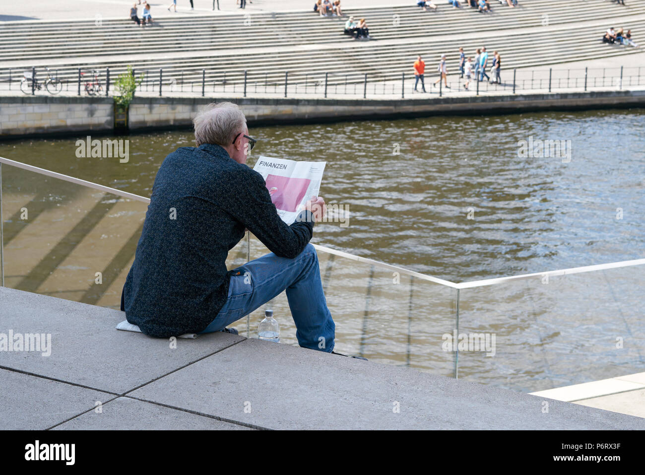 Un homme est assis sur un escalier et lit la partie financière d'un journal Banque D'Images