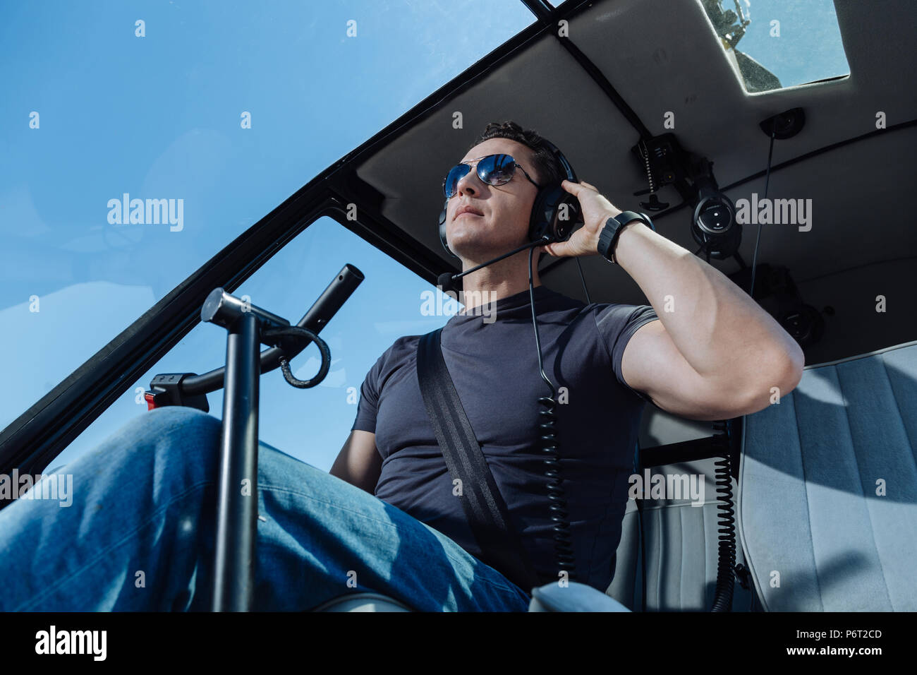 Pilote d'hélicoptère sérieux à l'écoute de contrôleur de la circulation aérienne Banque D'Images