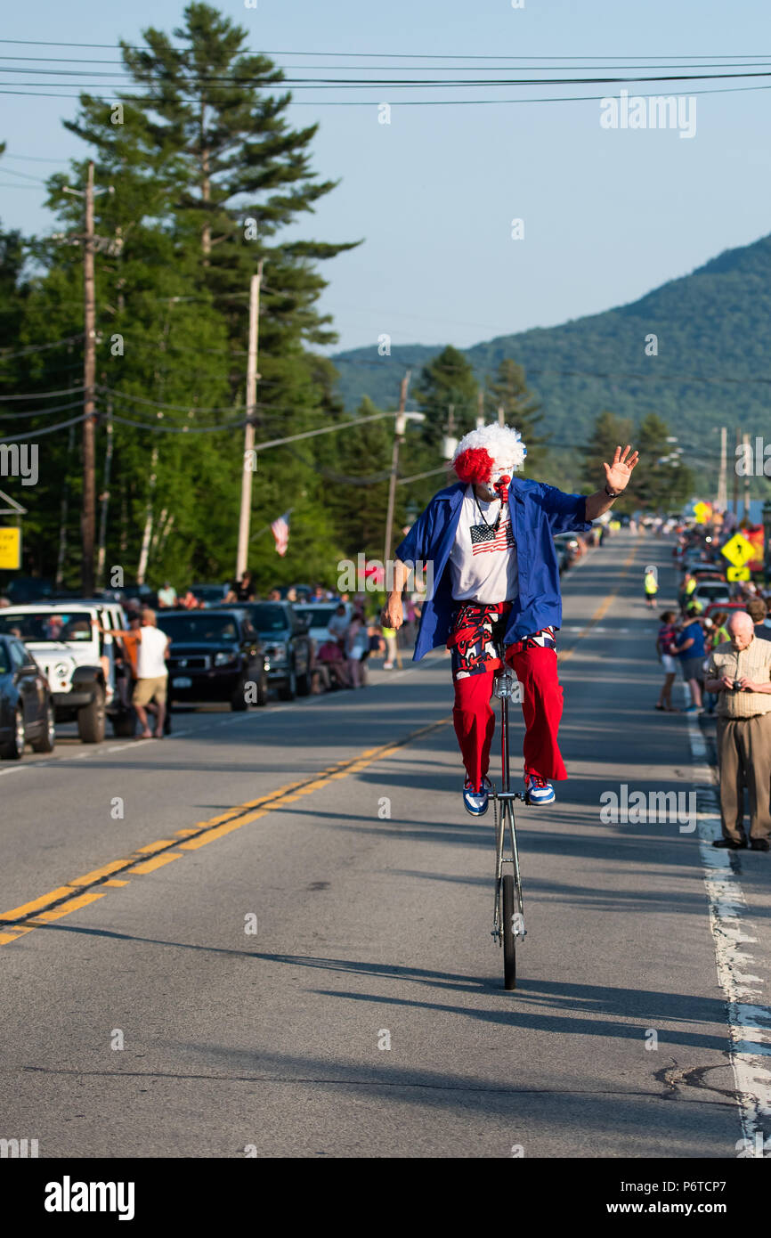 Un clown heureux en rouge, blanc et bleu équitation un monocycle dans le 4e de juillet parade qui s'est tenue le 30 juin 2018 en spéculateur, NY USA Banque D'Images
