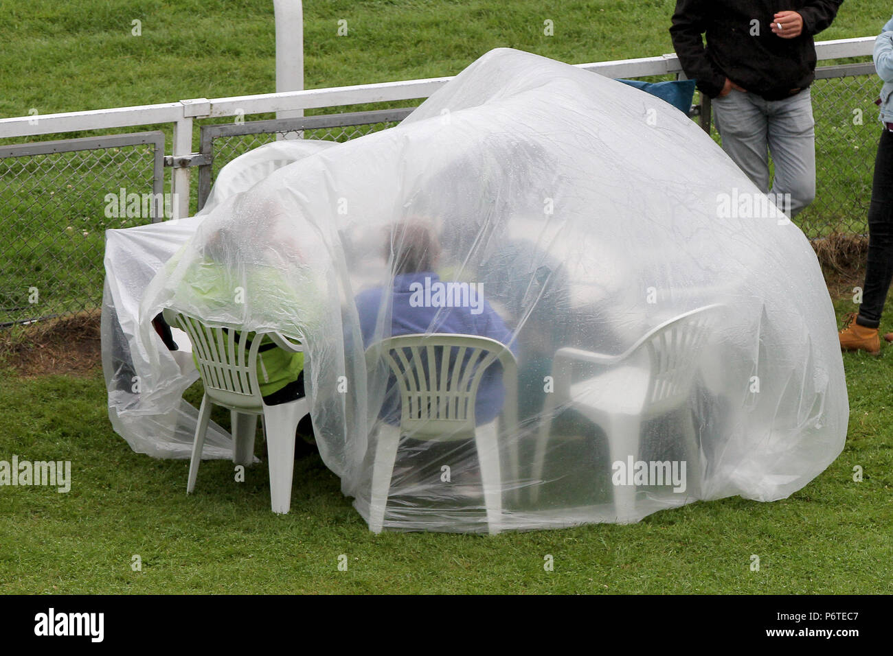 Hambourg, spectateurs assis dans la pluie sous une bâche de plastique à leur table sur la course Banque D'Images