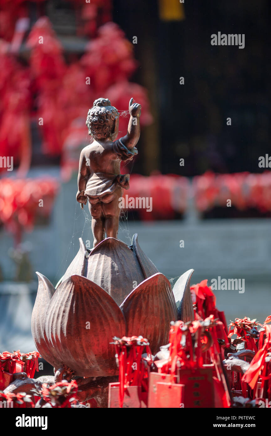 Statue de Bouddha debout sur une fleur de lotus avec bandes rouges dans LuoHanCi temple Chongqing, Chine Banque D'Images