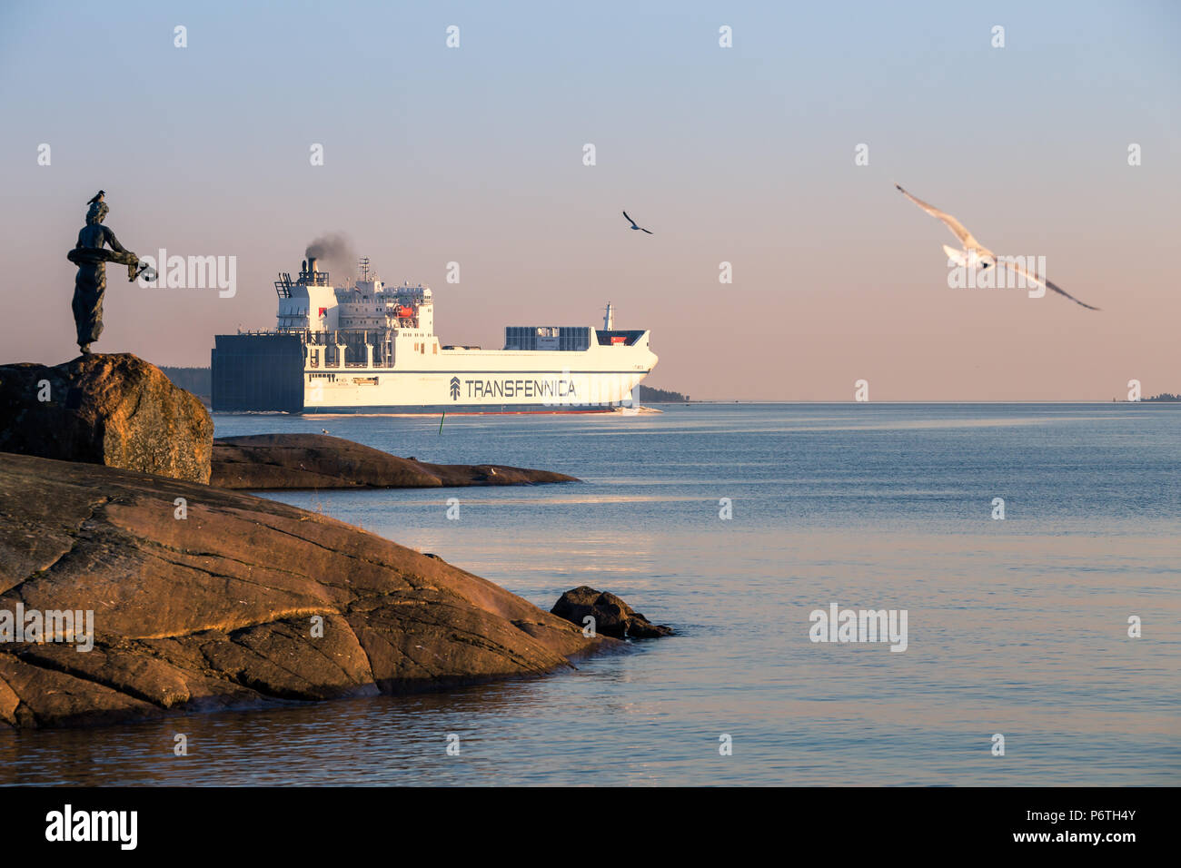 D'un cargo en direction de mer ouverte dans le coucher du soleil, Mouettes volantes et memorial statue de bataille de Svenksund en 1790 Kuussinen, Kotka, Finlande Banque D'Images