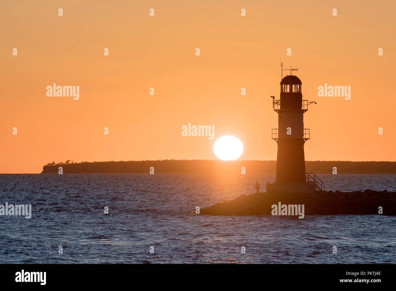 WarnemÃ¼Nde, district de Rostock, côte de la mer Baltique, Mecklembourg-Poméranie-Occidentale, en Allemagne. Man fishing au phare au lever du soleil. Banque D'Images