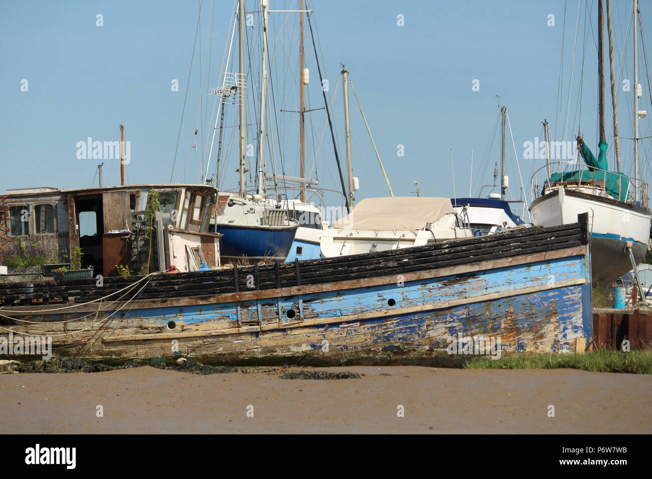 Décroissance côtières - un bateau en bois en décomposition d'épaves sur le rivage et le port. Essex, Angleterre. L'été 2018. Banque D'Images