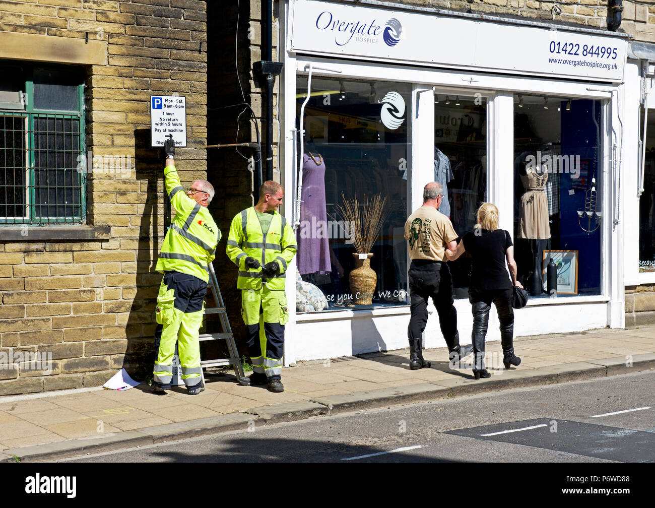 Les hommes l'installation de panneaux pour de nouvelles restrictions de stationnement à Hebden Bridge Calderdale, West Yorkshire, England, UK Banque D'Images