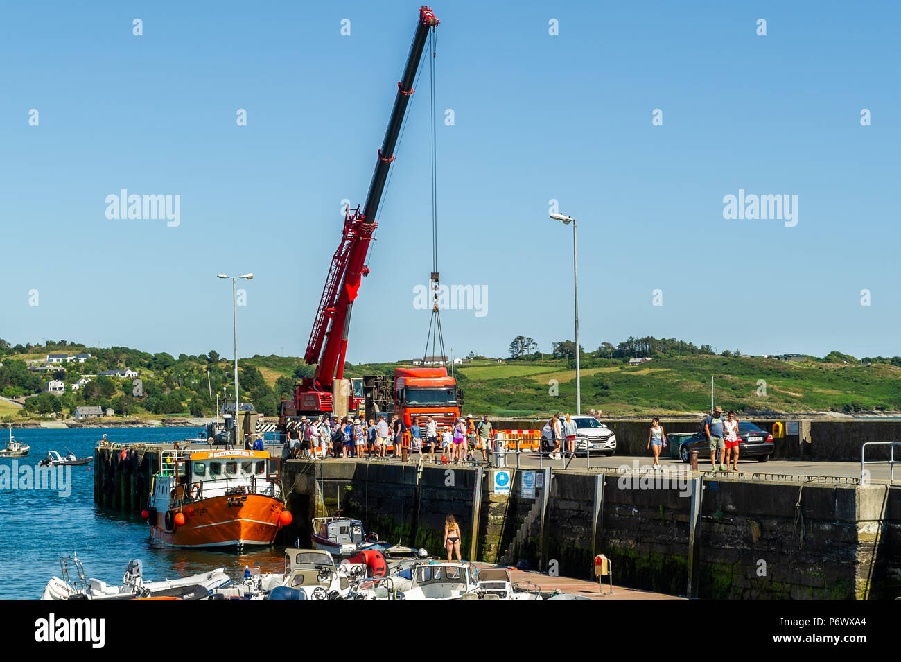 Schull, West Cork, Irlande. 3 juillet 2018. Les entrepreneurs lèvent une partie de la barge que les ouvriers utiliseront pour construire le nouveau ponton dans l'eau tandis que le ferry Cape Clear décharge ses passagers après un voyage sur l'île. Crédit : AG News/Alay Live News. Banque D'Images