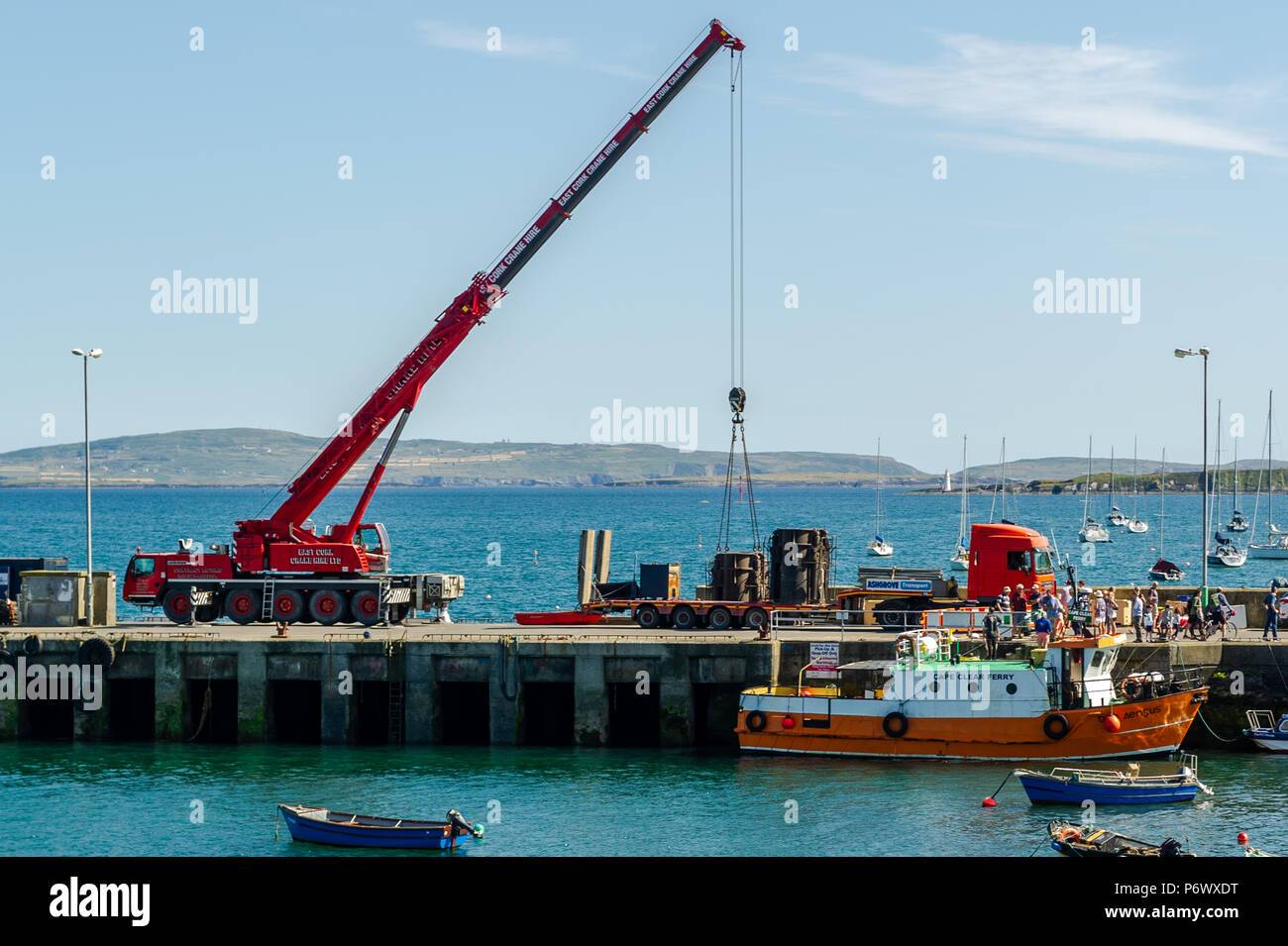 Schull, West Cork, Irlande. 3 juillet 2018. Les entrepreneurs lèvent une partie de la barge que les ouvriers utiliseront pour construire le nouveau ponton dans l'eau tandis que le ferry Cape Clear décharge ses passagers après un voyage sur l'île. Crédit : AG News/Alay Live News. Banque D'Images