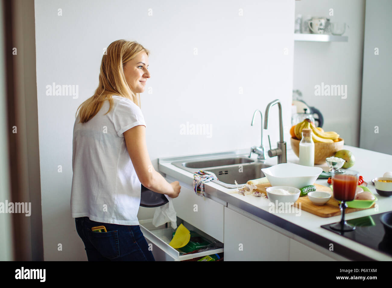 Jeune femme faisant des travaux ménagers courants chaque jour, le nettoyage de vaisselle dans la cuisine après le dîner Banque D'Images