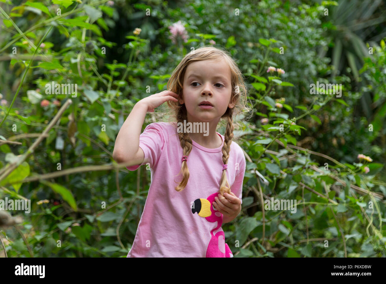 Portrait d'un enfant debout devant un fond de plantes vertes. Plan moyen. Banque D'Images