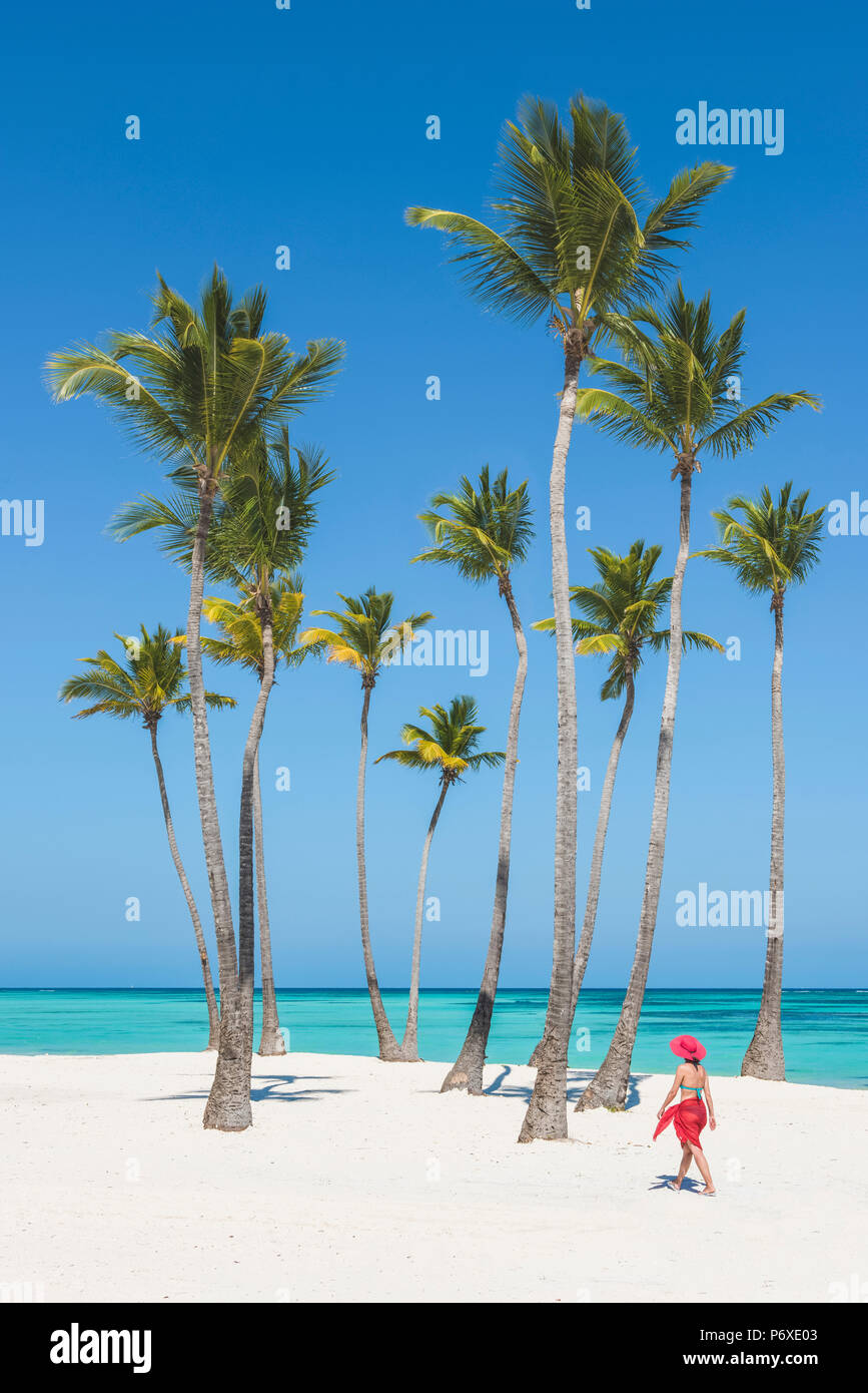 Juanillo Beach (playa Juanillo), Punta Cana, République dominicaine. Femme marche sur une plage bordée de palmiers (MR). Banque D'Images