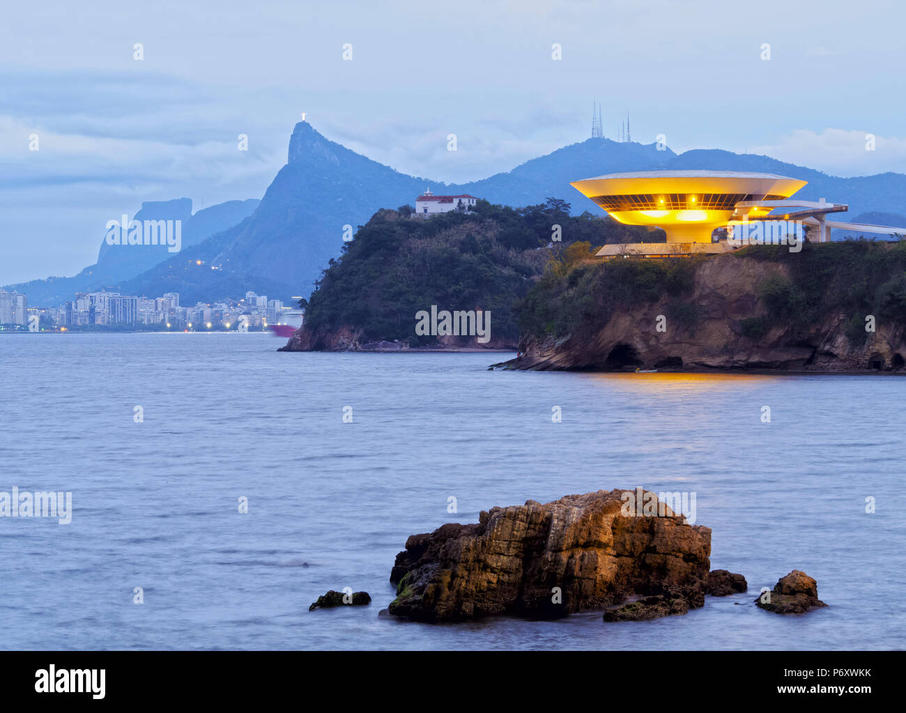 Brésil, État de Rio de Janeiro, Niteroi, Crépuscule vue sur le musée d'Art Contemporain de Niterói avec toits de Rio de Janeiro à l'arrière-plan. Banque D'Images