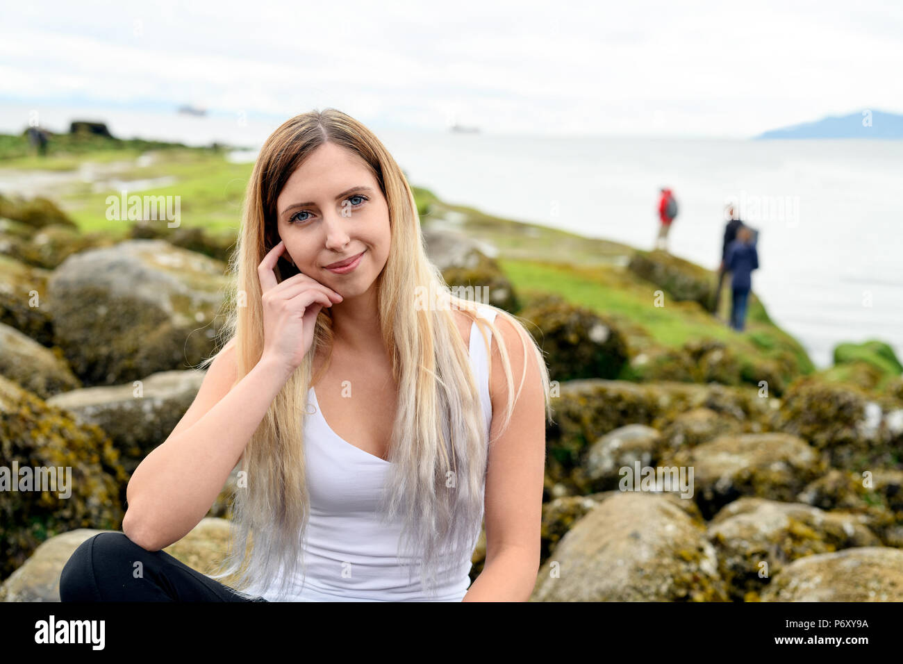 Young woman smiling et bienvenus dans l'appareil photo dans la zone intertidale de Vancouver, Colombie-Britannique. Ces roches sont à sous-marine Banque D'Images