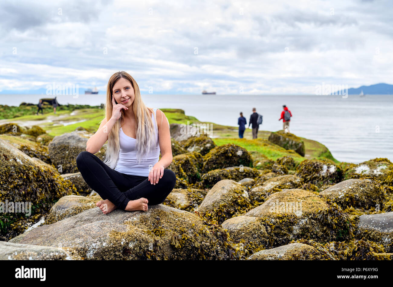 Young woman smiling et bienvenus dans l'appareil photo dans la zone intertidale de Vancouver, Colombie-Britannique. Ces roches sont à sous-marine Banque D'Images