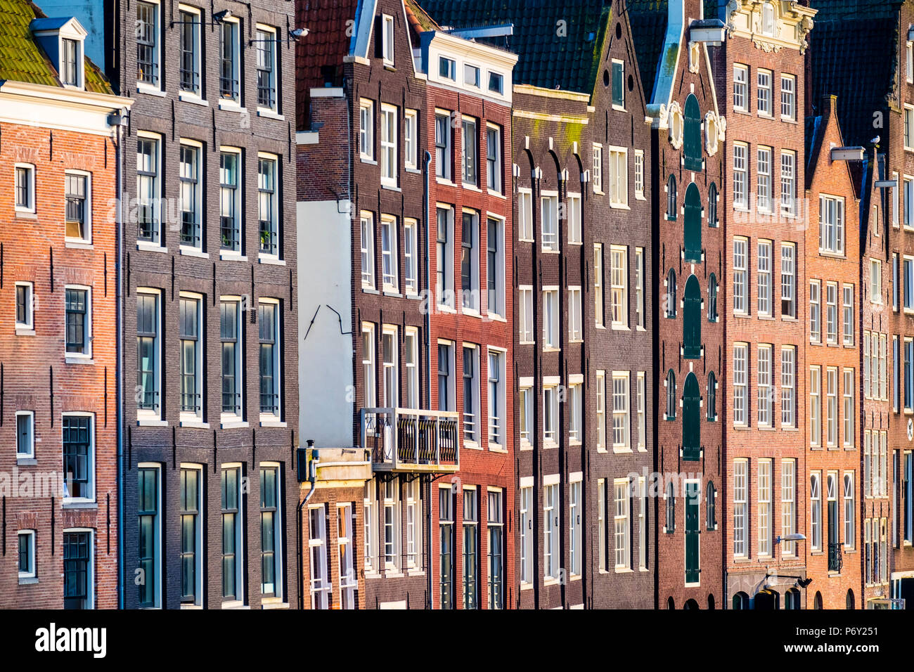 Pays-bas, Amsterdam, Hollande du Nord. Façades de maisons du canal de travers sur le Damrak. Banque D'Images