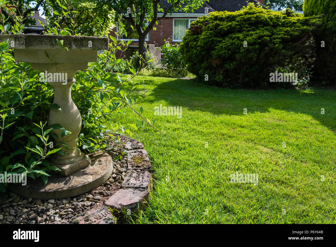 Un birdbath dans un joli jardin anglais sur une chaude journée ensoleillée. Banque D'Images