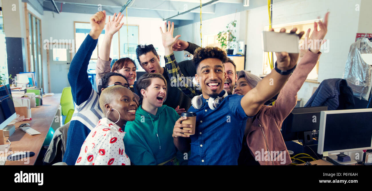 L'équipe entreprise créative enthousiaste en tenant en selfies office Banque D'Images