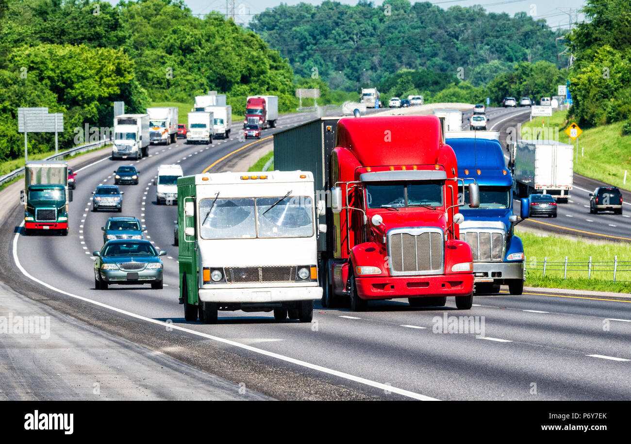 American couleurs reflètent dans trois camions conduisant le trafic sur une autoroute. Tourné sur chaude journée. Les vagues de chaleur de l'asphalte provoque une distorsion sur les véhicules loin Banque D'Images