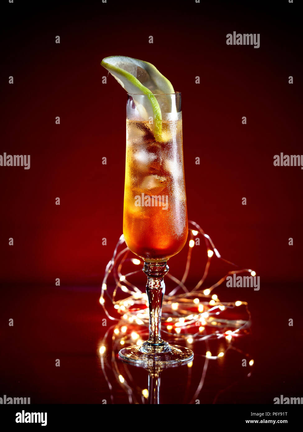 Aperol Spritz garnie avec une tranche de pamplemousse servi dans un grand verre sur un fond sombre avec des lumières de fête Banque D'Images
