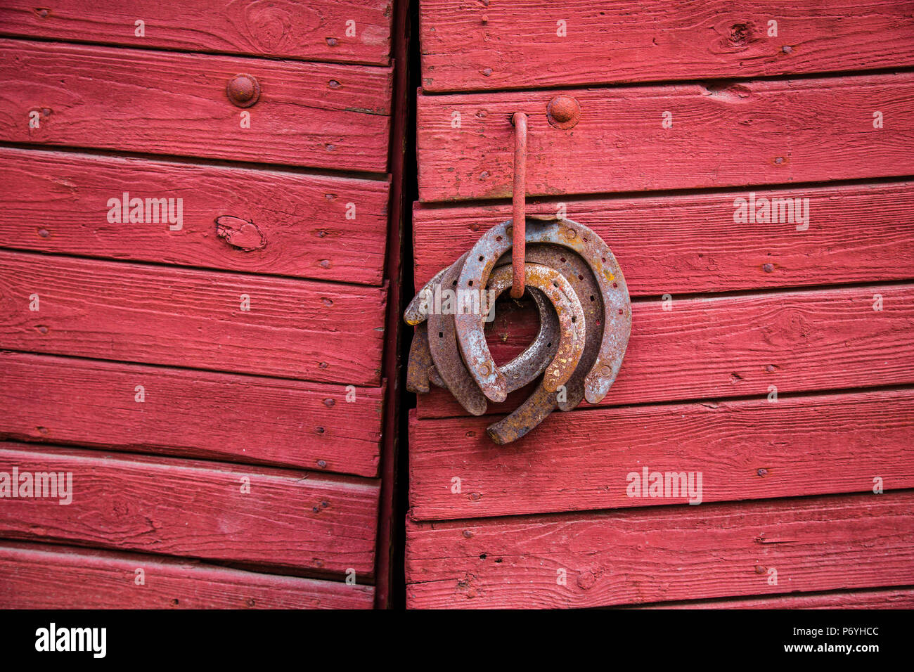 Old rusty fers accroché sur la poignée de porte en bois rouge Banque D'Images