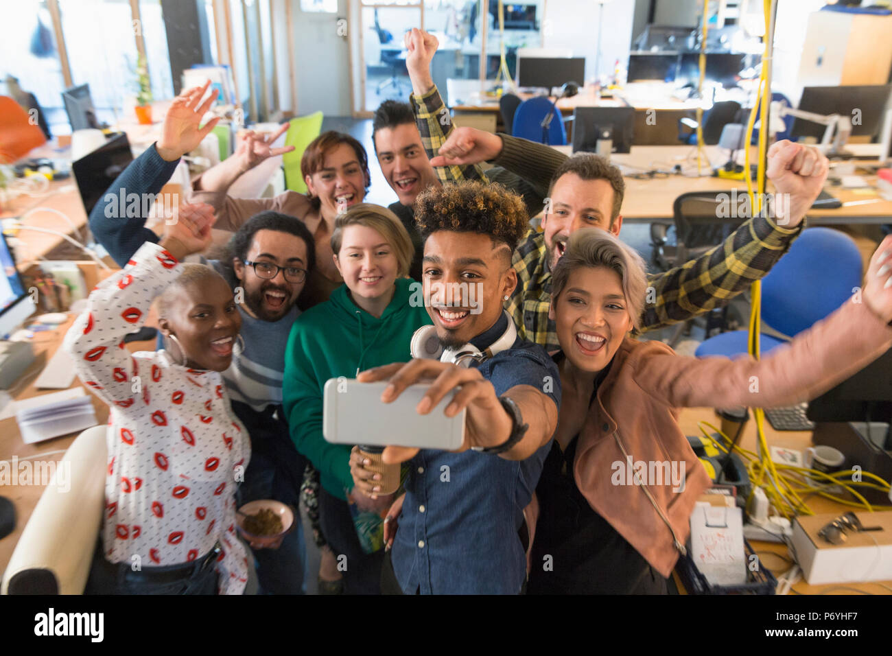 L'équipe d'affaires créatifs enthousiastes acclamations, prenant en selfies office Banque D'Images